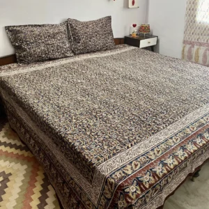 Brown and indigo Kalamkari double bedsheet with geometric print and butterfly border on a bed with two pillow covers