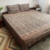 Black and mustard Kalamkari double bedsheet with leaf print and diamond border on a bed with two pillow covers
