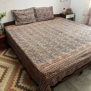 Black and mustard Kalamkari double bedsheet with leaf print and diamond border on a bed with two pillow covers