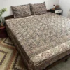Black and rust Kalamkari double bedsheet with paisley print and elephant border on a bed with two pillow covers