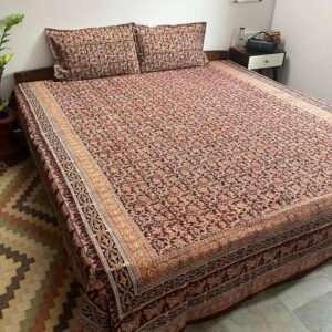 Coffee brown and mustard Kalamkari double bedsheet with floral creeper print and butterfly border on a bed with two pillow covers